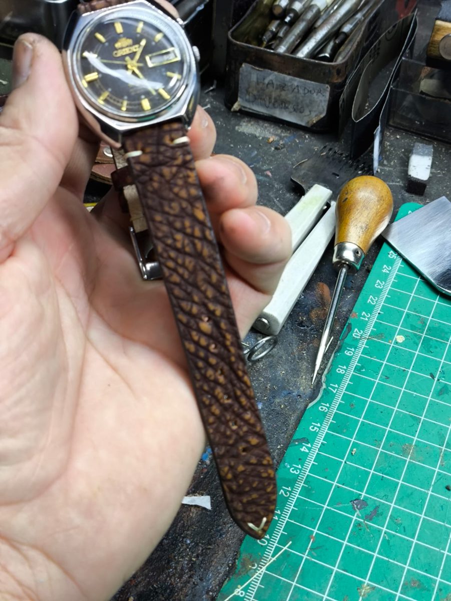 Bancada do atelier com ferramentas e um relógio com pulseira de couro