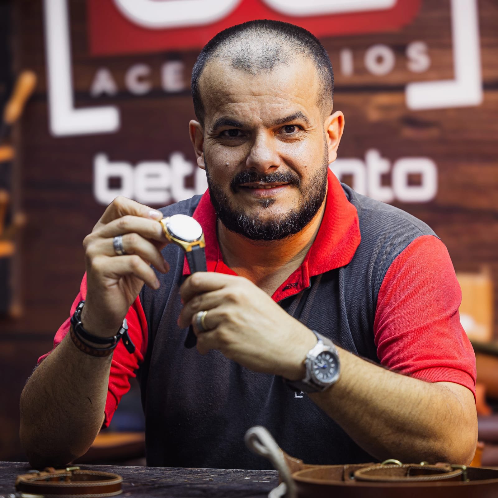 Beto Canto no atelier, segurando um relógio com pulseira de couro