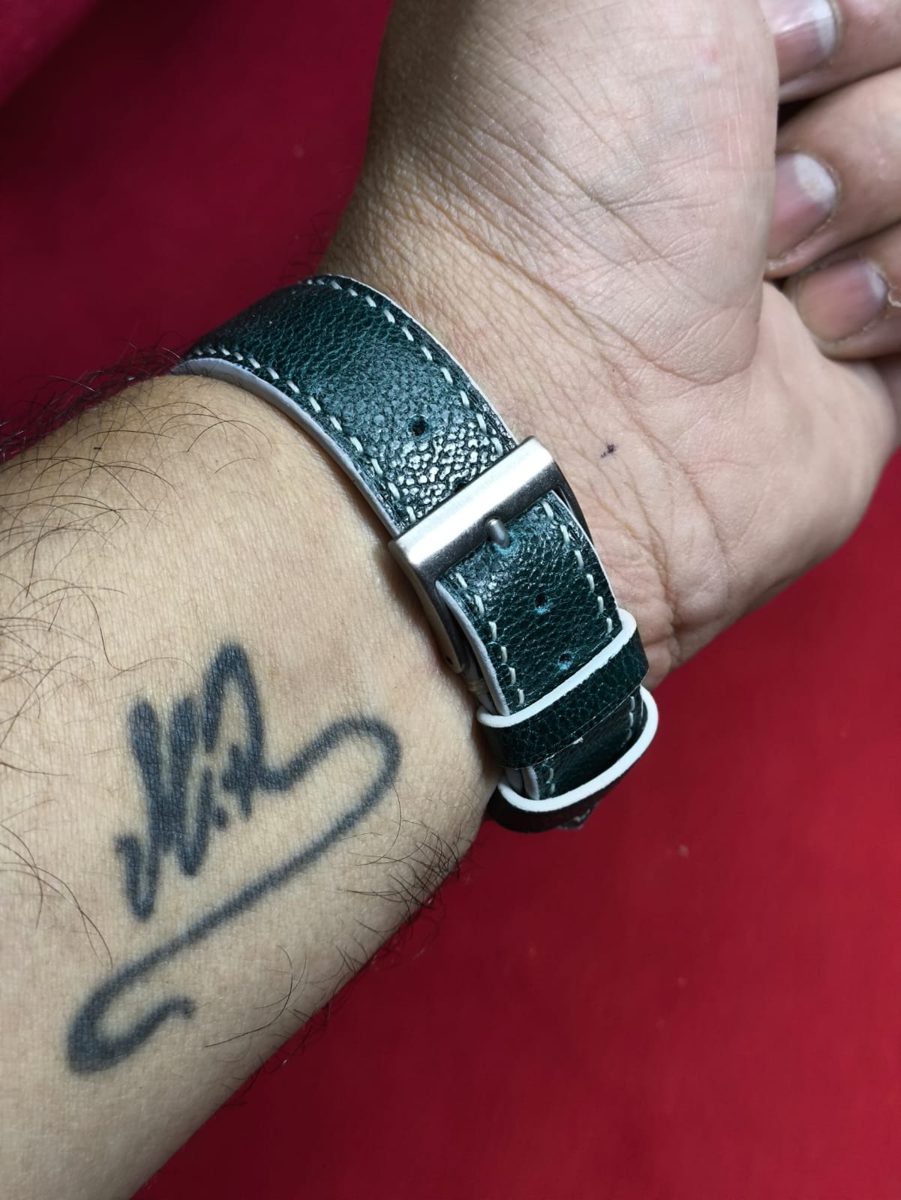Pulseira verde no pulso, sobre fundo vermelho