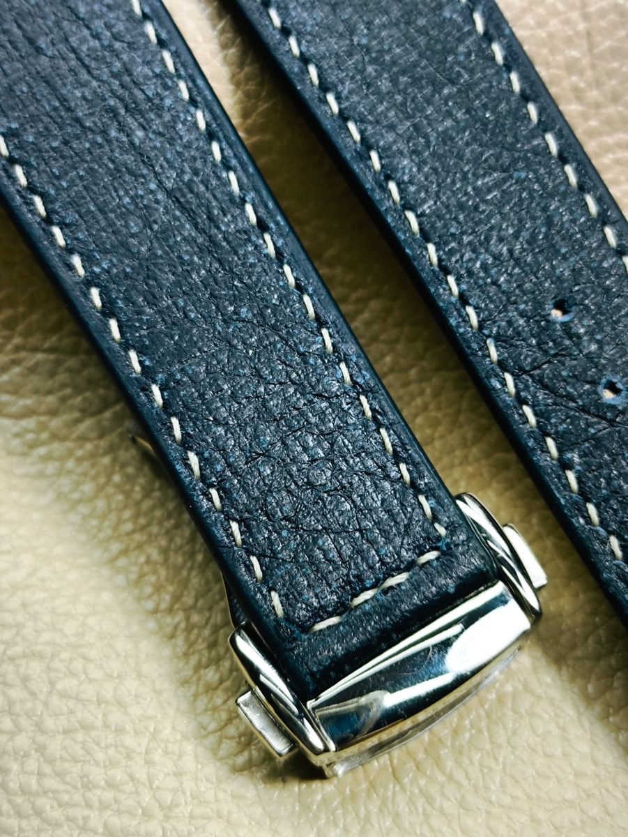 Close do pesponto creme em uma pulseira azul